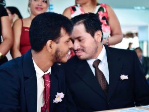 Dos hombres con trajes formales sonríen juntos durante una ceremonia de matrimonio civil.