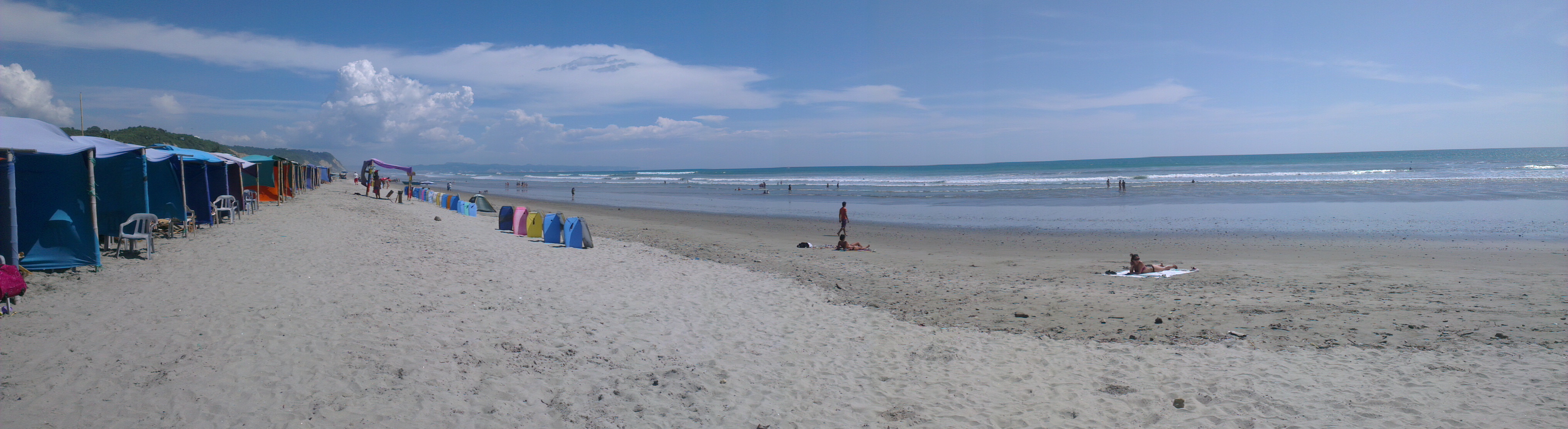 Vista de la playa de Canoa, en Manabí, con mar, arena y acantilados al fondo.